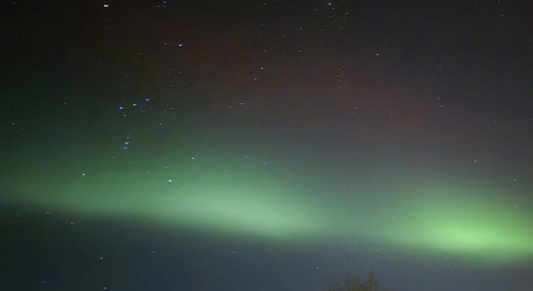 aurora borealis, intense green in the middle and a dim red wave above are visible