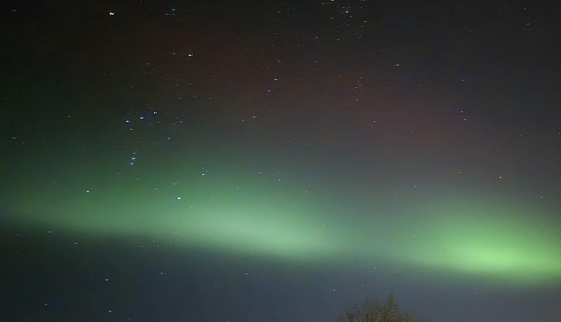 aurora borealis, intense green in the middle and a dim red wave above are visible
